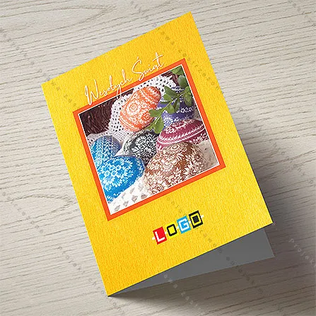 Zdobione pisanki w kolorach niebieskim, pomarańczowym, czarnym i brązowym na serwetce, obok biały kaligraficzny napis