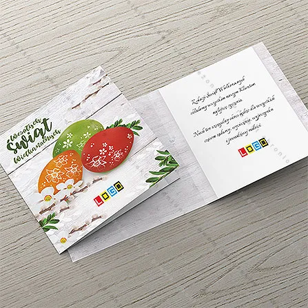 Zielone, pomarańczowe i czerwone jaja z białymi motywami, narcyzy i gałązki bazi na postarzanych deskach
